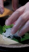 tonijn vis vlees met rijst- vermicelli Aan een vel verspreiding met saus besprenkeld mannetje handen in handschoenen koken in restaurant sushiya slim kijk maar Aan hand- de werkwijze van voorbereidingen treffen een duur schotel Aziatisch keuken video