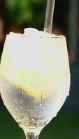 pour lemonade with ice Ice into a glass pour soda water throw lemon stir with a straw several s of a cold drink on the street on the table bubbling foam bubbles close-up video