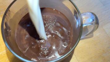 heet chocola melk gieten toevoegen koffie creamer in zwart koffie. langzaam beweging room gieten in een kop van zwart koffie video