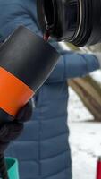 vrouw in groen jasje en handschoenen giet heet thee van een thermosfles in een mok thermosfles fles in de winter handen met leer handschoenen gieten heet thee koffie van geel thermosfles en drinken het in winter. video