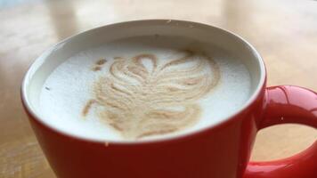 Latte art in red cup on wooden live edge table. hot coffee latte close up video