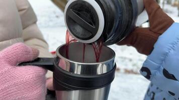 lento movimento avvicinamento di un' donna scrosciante caldo tè a partire dal un' thermos in un' boccale all'aperto nel il freddo tempo atmosferico. video