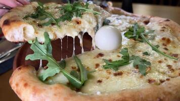 fermer de une cuit italien Pizza sur une en bois table dans une café. fermer. arrière-plans. Olives, roquette, Parmesan, jambon. ananas, saucisse, champignons. service. pizzeria. caméra mouvement. banquet. video