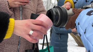 Pouring mulled wine in to cup with orange slice, in the magic winter landscape. Backpack traveling in white mountains. Winter mountain trekking in stunning white scenery. video