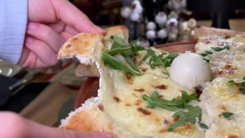 fechar-se do uma chefe de cozinha derramando pesto molho em uma recentemente cozido pizza com stracciatella queijo dentro uma tradicional italiano pizzaria. video