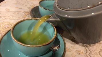 oblipich gember thee groen kop gember thee in een kop en gehakt wortel in een kom Aan de tafel. natuurlijk vitamines. video