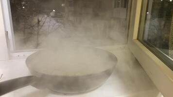 windowsill steam frying pan Winter evening snow on the street steam comes from cooked Asian cuisine meat with asparagus cooling the dish in a frying pan video