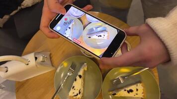 hands of a girl teenager women filming lunch in a cafe apple tart with cream and chocolate And hot chocolate with cream on a wooden table fork plate food in a restaurant video