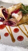 Cooking art. Chef spreading caramel on top of stack of fresh fluffy pancakes decorated with forest berries. Homemade Healthy Vegan Fluffy American Style Pancakes with Fresh Fruits. Pouring honey on video