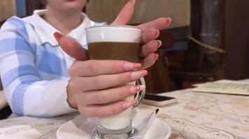 muito grandes unhas manicure Rosa gel polonês falso unhas menina com cappuccino dentro uma restaurante irreconhecível pessoas mãos bebendo café com leite beber quente vidro caneca Palha Preto azul xadrez suéter video