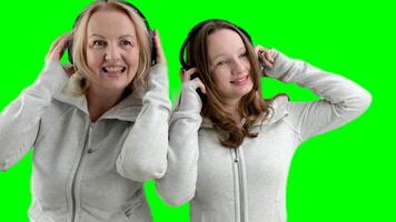 mother and daughter in headphones make eyes, smile, take pictures, family photo session identical clothes, beautiful people, women, teenager and adult woman, expression of surprise on the face, smile video