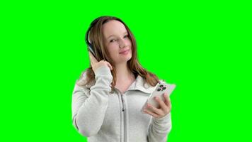 girl with headphones and a mobile phone at a photo shoot studio white background keep a finger on the headphones make eyes pose mobility music listen track sportswear play sports video