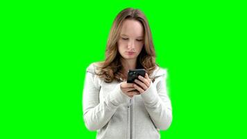 Portrait of tense concentrated female teenager with very long brown hair playing game on her cell phone being winner gesturing in joy over white background. Concept of emotions video