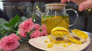 lado ver sonriente talla extra mujer mirando a amarillo francés macarrón con caramelo Formación de hielo en pie adentro. retrato de satisfecho caucásico panadero admirativo dulce delicioso Pastelería en lento movimiento video