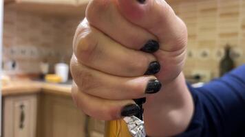 apertura champán a hogar, el mano de un rechoncho mujer con un negro manicura abre un corcho en champán en cocina, ordinario departamento, real personas de cerca botella cuello celebrando a hogar con familia video