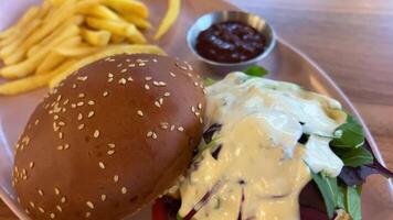 Hamburger and fried potatoes on wooden table Ordered fast food burger and fries with beer in a restaurant video