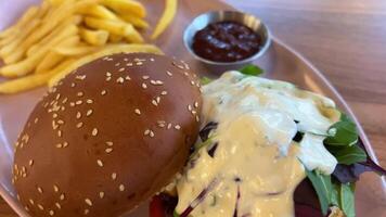 Hamburger and fried potatoes on wooden table Ordered fast food burger and fries with beer in a restaurant video