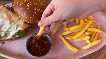 Woman dipping delicious French fries into sauce, closeup video