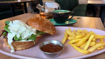 lunch snack in a restaurant french fries with ketchup delicious burger with blue cheese arugula tomatoes lots of sauce white tea, Canadian American food European lunch fast food video