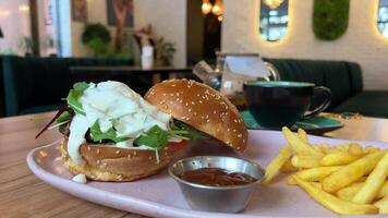 dichtbij omhoog schot van hamburger, aardappel Patat en salade Aan een wit bord houten tafel. video