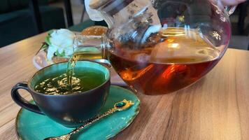 tè essere versato in tradizionale Cinese tè tazza su il tavolo, caldo bevanda bevanda rinfresco tè volta. video
