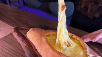 Hand mixing ingredients of adjarian khachapuri with fork in restaurant. Open bread pie with cheese and egg yolk. Yummy georgian cuisine. Slow motion. video