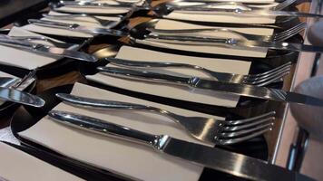serving knives and forks on white napkins on a large long table preparation for a corporate event of a large company cutlery Knife and fork prepared on an empty table in a restaurant video