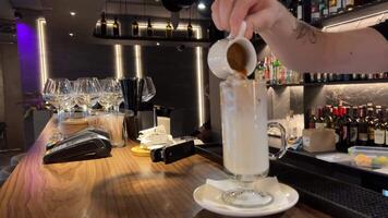 Leche crema es vertido dentro un con hielo café. café frío bebida con hielo y leche. video