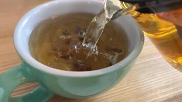 versare erbaceo tè in un' tazza di verde tè con blu fiordalisi. carpazi caldo bevanda durante il freddo stagione, tradizionale popolare trattamento per influenza e raffreddori. video
