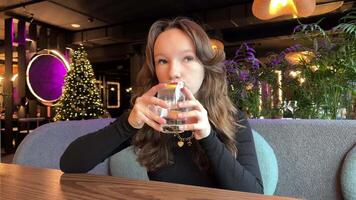dryck vatten med citron- diet rätt näring hälsa fördelar ung flicka i en restaurang med glas av ren vatten innan äter friska för vikt förlust ljus röd läppstift svart kväll klänning europeisk. video