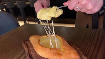 Hand mixing ingredients of adjarian khachapuri with fork in restaurant. Open bread pie with cheese and egg yolk. Yummy georgian cuisine. Slow motion. video