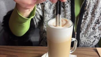 Hand stirs coffee foam spoon, health-conscious routine. mindful preparation coffee, health aspect enjoying lighter, foam-topped brew. health-aware choices daily life part healthy lifestyle commitment. video