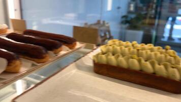 mostrador lleno de delicioso bollos y pasteles en comercio, panadería manojo de ecler Pastelería cubierto con chocolate apilado en parte superior de cada otro a el comida mercado video