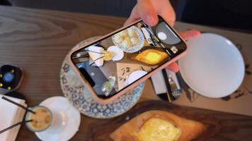 un muchachas mano toma imágenes de comida en un georgiano restaurante, khachapuri Khinkali agua con limón y aislar tomar fotos y s para social redes en Internet Blog blogger comida video