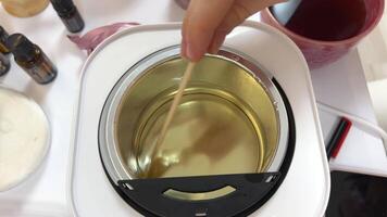 The process of making a massage candle using ingredients oils and wax measure weigh stir add close-up of women's hands. food thermometer measure wax temperature women's party women witches witchcraft video