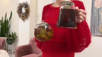 choice of black and green tea in the hands of a woman in red two glass teapots offering drinks tea party hen party master class, refreshments unrecognizable people video