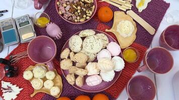 on table massage candles in form of roses Libra and various sweets nuts, purple pink cups fruits cooking making fragrant candles with marshmallows and meringues on plate Brazil nuts and dried fruits video