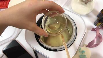 The process of making a massage candle using ingredients oils and wax measure weigh stir add close-up of women's hands. food thermometer measure wax temperature women's party women witches witchcraft video