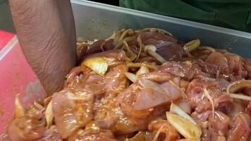 voorbereidingen treffen kip Vleugels voor Koken. de kip Vleugels zijn gemengd met de saus in een pan. detailopname van een koken roeren kip Vleugels in een pan. kip Vleugels in zoet en verzuren saus. video