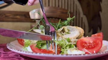 Cesare insalata crostini microgreens piselli pomodori su un' bianca piatto rosso tovaglia nel un' ristorante Quaglia uova lattuga con salsa mangiare nel un' ristorante posate forchetta coltello video