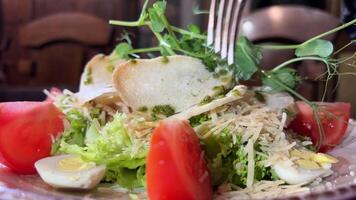 caesar sallad krutonger mikrogrönsaker ärtor tomater på en vit tallrik röd bordsduk i en restaurang vaktel ägg sallad med sås äta i en restaurang bestick gaffel kniv video