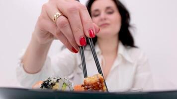 Sticks Take Sushi in restaurant lights background. Variety of types sushi with red caviar, fish, Philadelphia cheese and chopsticks close-up. Set of delicious Japanese sushi rolls on a stone board video