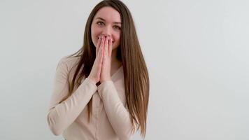glücklich süß jung Mädchen gefaltet ihr zwei Hände in der Nähe von ihr Mund wie wenn im Gebet Abdeckung ihr Mund lächelt sieht aus richtet sich auf ihr Haar auf ein Weiß Hintergrund Schönheit Pflege weiblich Attraktivität video