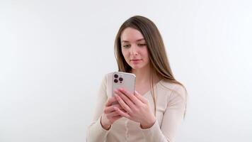 Young woman using cellphone, swiping and texting message, grey background video