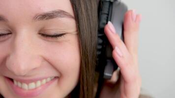 fechar-se retrato do adorável jovem mulher desfrutando música usando fones de ouvido, isolado sobre branco video