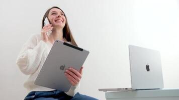 nuevo tecnologías manzana macbook 14 Pro teléfono iphone 13 Pro max y ipad en un blanco antecedentes el niña usos todas el último tecnologías hablando en el teléfono sonriente participación un tableta mirando a un ordenador portátil video