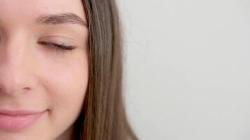 close-up half face place for text ad beauty grooming cream young smiling woman looking happy on white background. Big smile on her face, looking beautiful and cute with hands touching her cheek. video