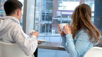 boy and girl teenagers in cafe sit by window talking having fun having fun first date relationship school cafeteria restaurant relaxing drinking coffee spending a day in city life of real people video