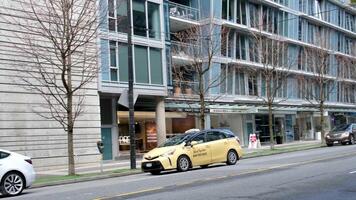 Vancouver straat wolkenkrabbers bloeiend sakura voorjaar auto's verschillend gebouwen weg echt leven in de groot stad Vancouver Canada 2023 video