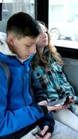 Interior of crowded bus with passengers listening to music and using mobile phone. two teenagers in blue clothes sit on a bus Canada Vancouver hoods autumn winter spring tracksuits use a mobile phone video